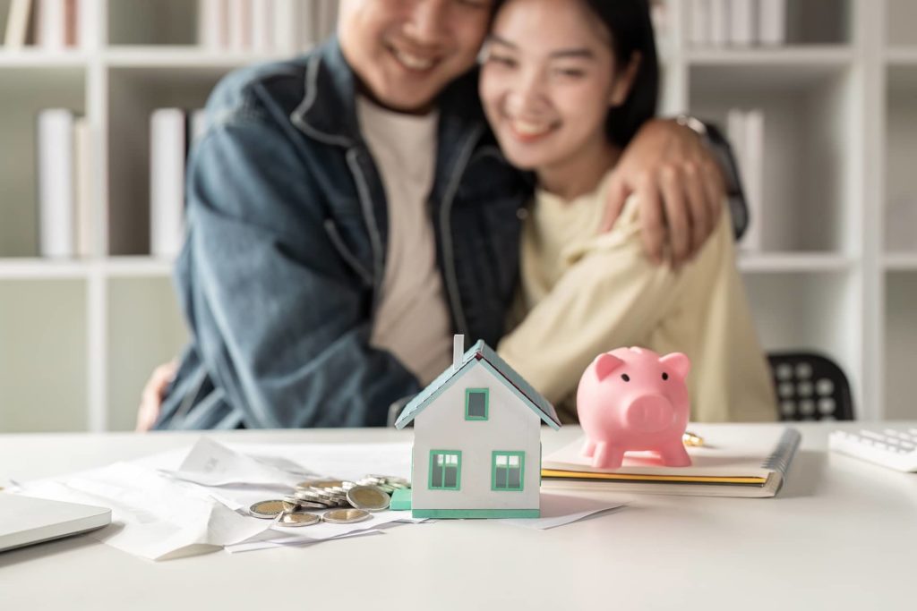 Pareja planificando su hipoteca con una maqueta de vivienda y una hucha