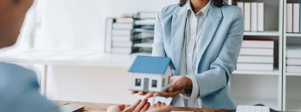 Asesora entregando una maqueta de vivienda para contratar un seguro de hogar