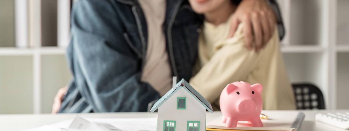 Pareja planificando su hipoteca con una maqueta de vivienda y una hucha